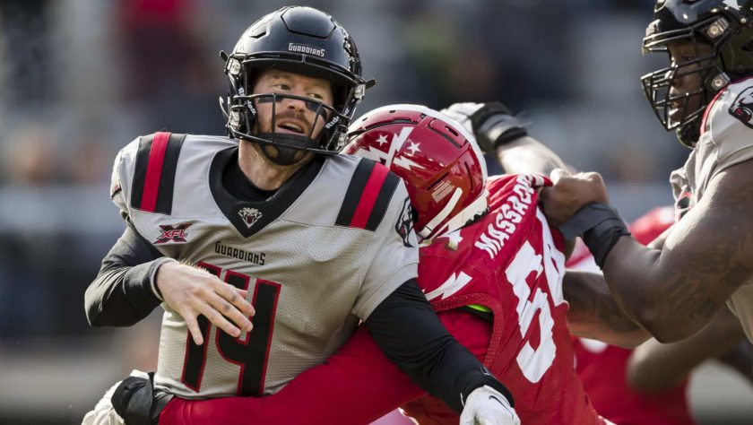 WASHINGTON, DC - FEBRUARY 15: Matt McGloin #14 of the NY Guardians is hit by Jonathan Massaquoi #54 of the DC Defenders during the first half of the XFL game at Audi Field on February 15, 2020 in Washington, DC.