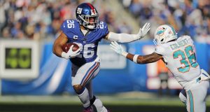 New York Giants running back Saquon Barkley (26) runs past Miami Dolphins free safety Adrian Colbert (36) during the first half of an NFL football game, Sunday, Dec. 15, 2019, in East Rutherford, N.J.