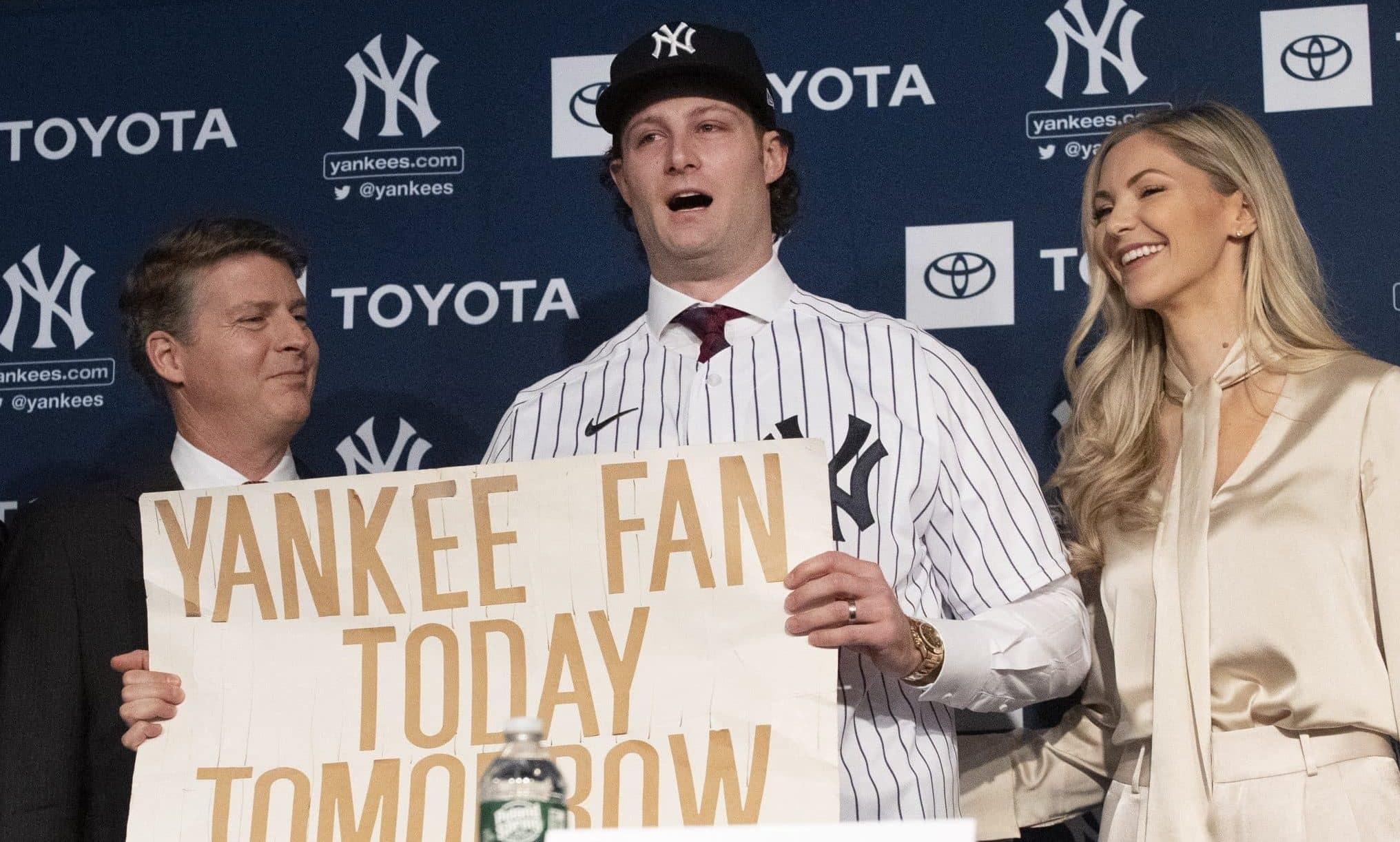 New York Yankees pitcher Gerrit Cole, center, holds a sign he used as a young Yankees fan, as he is introduced as the baseball clubs newest player during a baseball media availability, Wednesday, Dec. 18, 2019 in New York. He is joined by team owner Hal Steinbrenner, left, and his wife, Amy Cole.