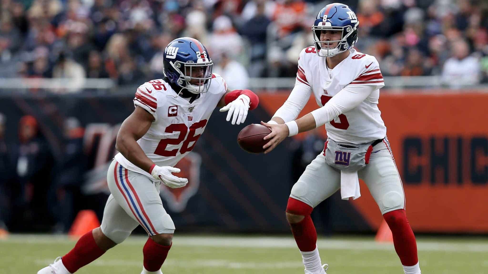 CHICAGO, ILLINOIS - NOVEMBER 24: Daniel Jones #8 of the New York Giants hands the ball off to Saquon Barkley #26 in the second quarter against the Chicago Bears at Soldier Field on November 24, 2019 in Chicago, Illinois.