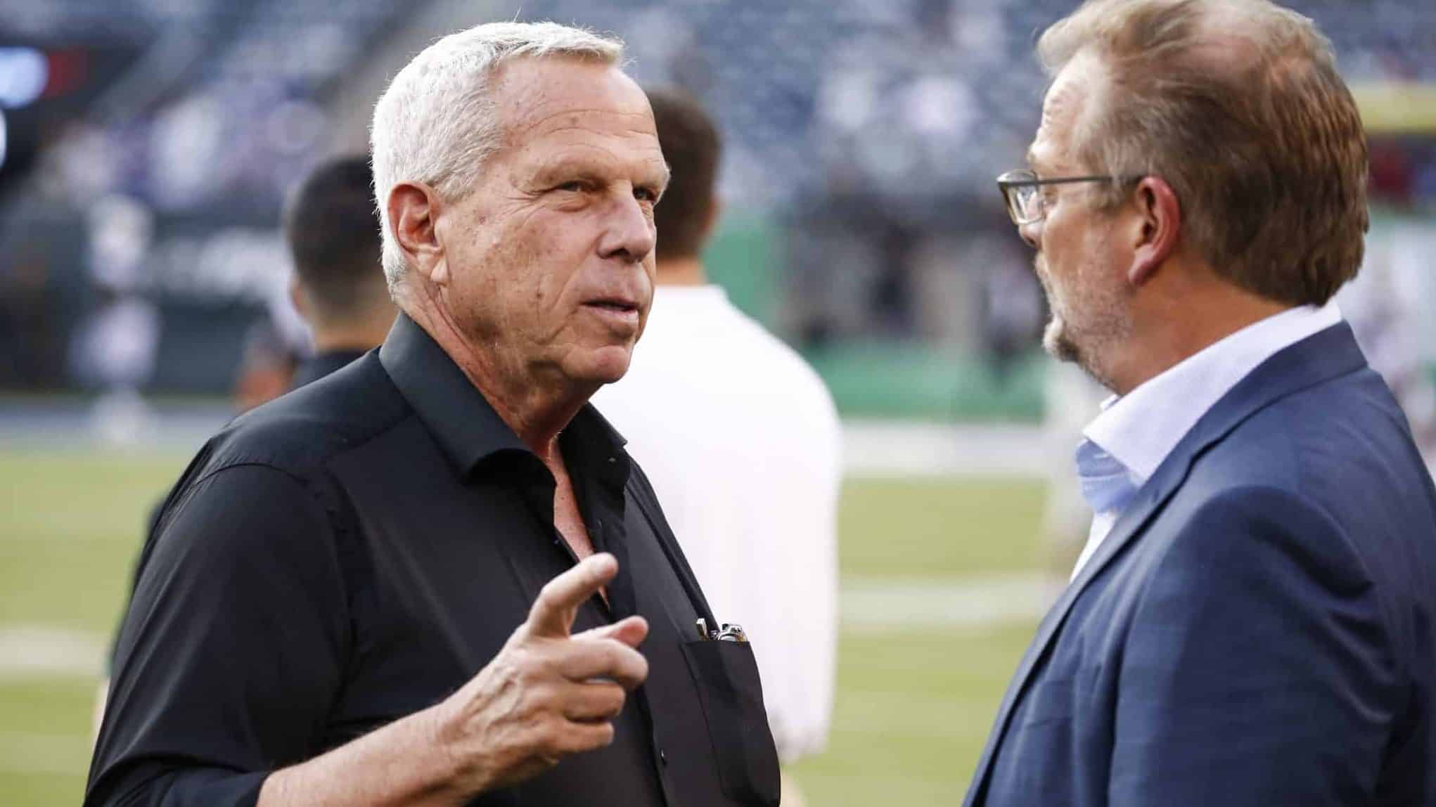 EAST RUTHERFORD, NJ - AUGUST 24: New York Giants chairman Steve Tisch talks with New York Jets GM Mike Maccagnan on the sidelines before a preseason game against the New York Jets at MetLife Stadium on August 24, 2018 in East Rutherford, New Jersey.