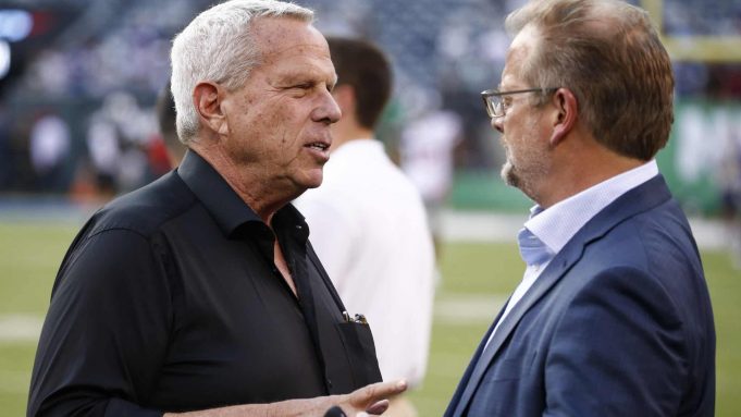 EAST RUTHERFORD, NJ - AUGUST 24: New York Giants chairman Steve Tisch talks with New York Jets GM Mike Maccagnan on the sidelines before a preseason game against the New York Jets at MetLife Stadium on August 24, 2018 in East Rutherford, New Jersey.