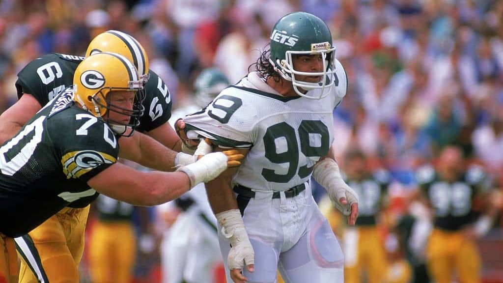 AUGUST 27: Defensive end Mark Gastineau #99 of the New York Jets gets held by a Green Bay Packers linemen during a preaseson game on August 27, 1988.