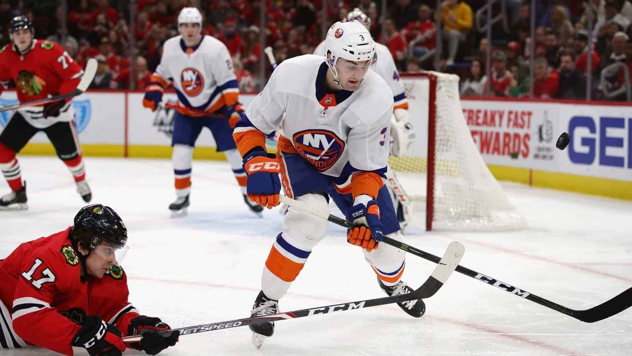 CHICAGO, ILLINOIS - DECEMBER 27: Dylan Strome #17 of the Chicago Blackhawks hits the ice as he knocks the puck away from Adam Pelech #3 of the New York Islanders at the United Center on December 27, 2019 in Chicago, Illinois.