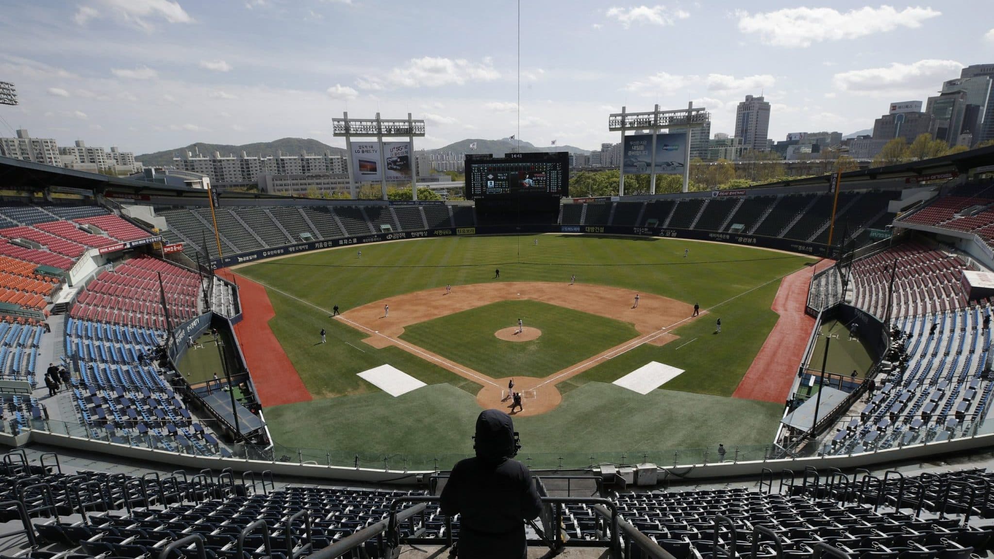 A TV cameraman films in the empty stadium as a part of precaution against the new coronavirus during the pre-season baseball game between Doosan Bears and LG Twins in Seoul, South Korea, Tuesday, April 21, 2020. South Korea's professional baseball league has decided to begin its new season on May 5, initially without fans, following a postponement over the coronavirus.
