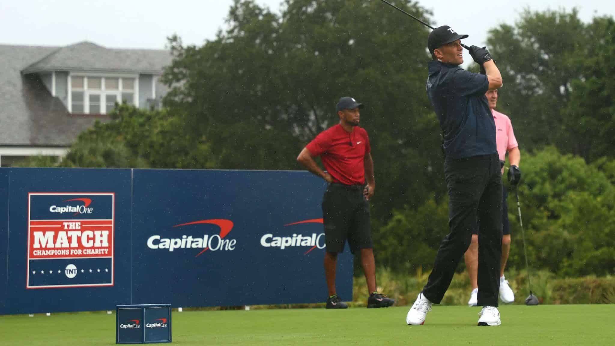 HOBE SOUND, FLORIDA - MAY 24: NFL player Tom Brady of the Tampa Bay Buccaneers plays his shot from the first tee as Tiger Woods an former NFL player Peyton Manning look on during The Match: Champions For Charity at Medalist Golf Club on May 24, 2020 in Hobe Sound, Florida.