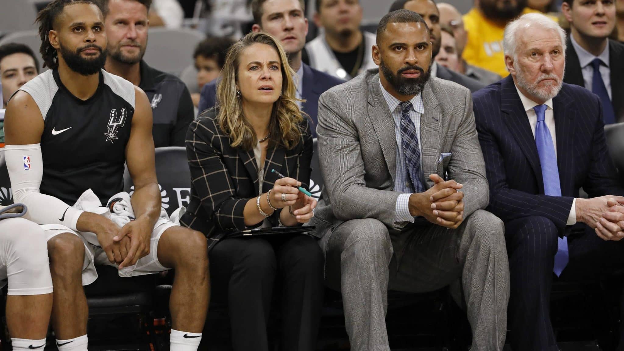 SAN ANTONIO, TX - OCTOBER 24: Patty Mills #8 of the San Antonio Spurs, assistant coaches Becky Hammon, Ime Udoka, and head coach Gregg Popovich watch action against the Indiana Pacers from the bench during an NBA game on October 24, 2018 at the AT&T Center in San Antonio, Texas. The Indiana Pacers won 116-96. NOTE TO USER: User expressly acknowledges and agrees that, by downloading and or using this photograph, User is consenting to the terms and conditions of the Getty Images License Agreement.
