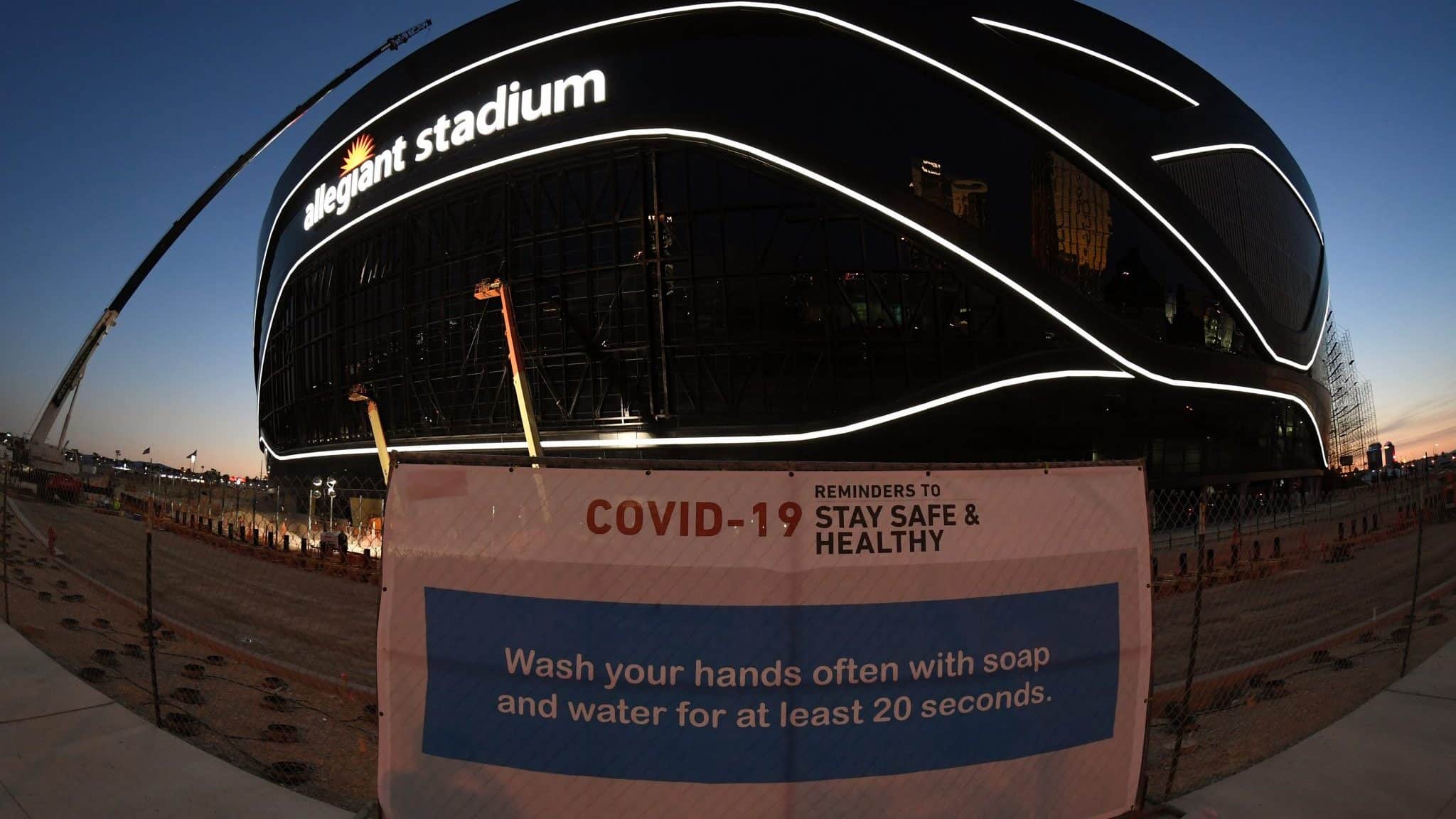 LAS VEGAS, NEVADA - APRIL 23: (EDITORS NOTE: This image was shot with a fisheye lens.) A sign with guidelines for how to stay safe from the coronavirus is posted on a fence while crews test out architectural light ribbons and exterior sign lighting as construction continues at Allegiant Stadium, the USD 2 billion, glass-domed future home of the Las Vegas Raiders on April 23, 2020 in Las Vegas, Nevada. The Raiders and the UNLV Rebels football teams are scheduled to begin play at the 65,000-seat facility in their 2020 seasons. The World Health Organization declared the coronavirus (COVID-19) a pandemic on March 11th.