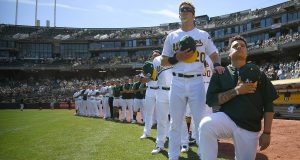 OAKLAND, CA - SEPTEMBER 24: Bruce Maxwell #13 of the Oakland Athletics kneels in protest next to teammate Mark Canha #20 duing the singing of the National Anthem prior to the start of the game against the Texas Rangers at Oakland Alameda Coliseum on September 24, 2017 in Oakland, California. New York Mets