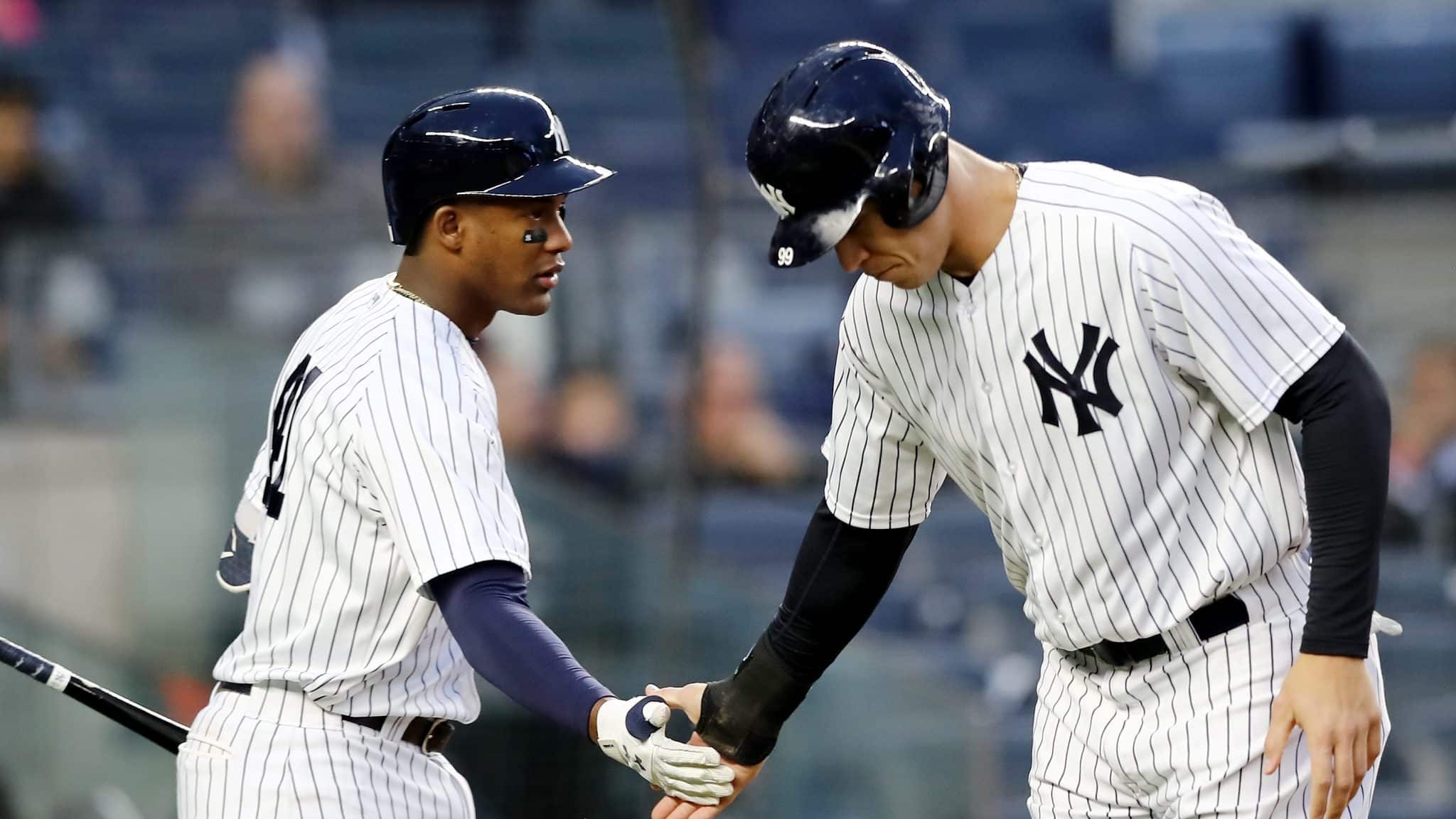 NEW YORK, NY - APRIL 16: Miguel Andujar #41 of the New York Yankees congratulates teammate Aaron Judge #99 after he scored on a bases loaded walk in the first inning against the Miami Marlins at Yankee Stadium on April 16, 2018 in the Bronx borough of New York City.