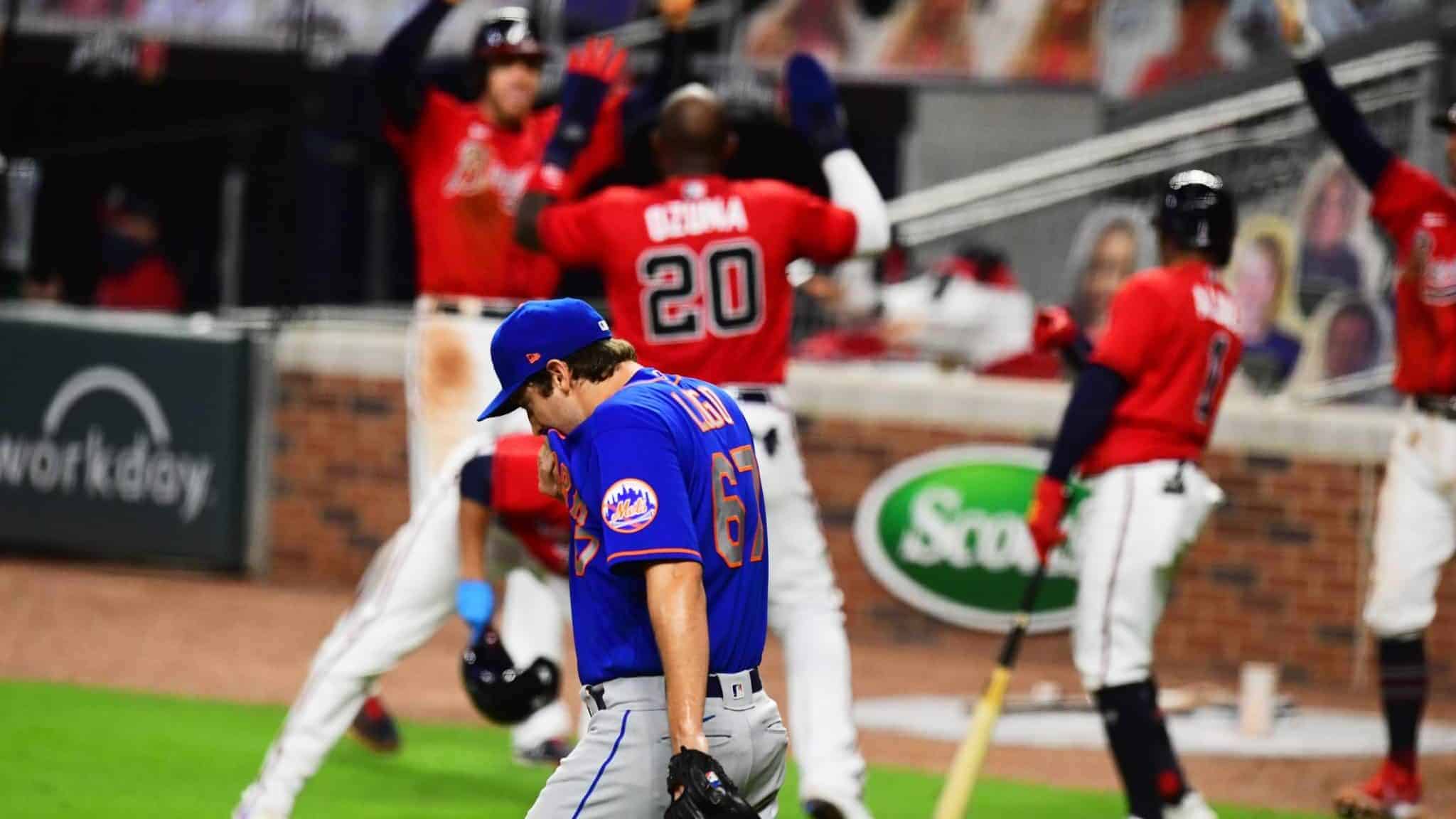 ATLANTA, GA - JULY 31: Seth Lugo #67 of the New York Mets heads back to the mound while members of the Atlanta Braves celebrate an eighth inning rally at SunTrust Field on June 31, 2020 in Atlanta, Georgia.
