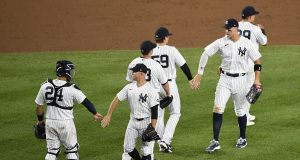 NEW YORK, NEW YORK - AUGUST 03: The New York Yankees high-five after winning 6-3 against the Philadelphia Phillies at Yankee Stadium on August 03, 2020 in the Bronx borough of New York City.