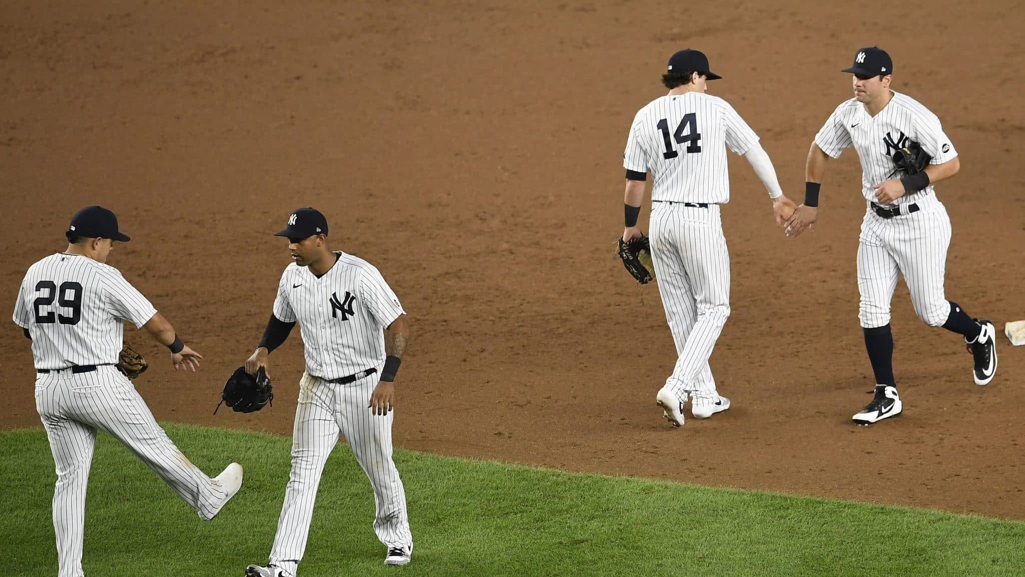 NEW YORK, NEW YORK - AUGUST 11: Gio Urshela #29, Aaron Hicks #31, Tyler Wade #14, and Mike Tauchman #39 of the New York Yankees celebrate after the ninth inning against the Atlanta Braves at Yankee Stadium on August 11, 2020 in the Bronx borough of New York City. The Yankees won 9-6.