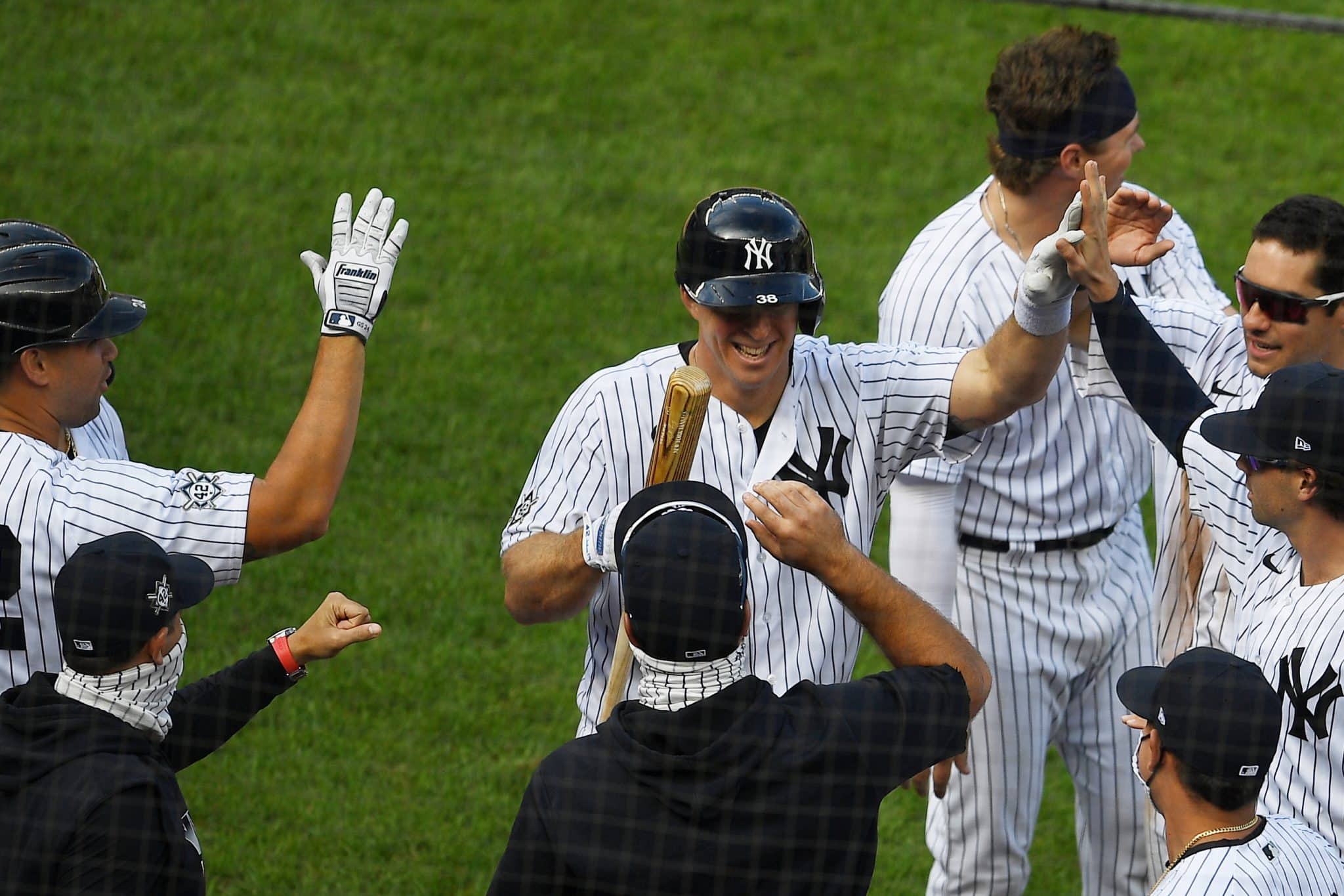 NEW YORK, NEW YORK - AUGUST 29: The New York Yankees high-five Erik Kratz #42 (C) after his at-bat where he attempted to bunt, allowing teammate Clint Frazier #42 (not pictured) to score on a wild pitch during the ninth inning against the New York Mets at Yankee Stadium on August 29, 2020 in the Bronx borough of New York City. The Yankees won 2-1. All players are wearing #42 in honor of Jackie Robinson Day. The day honoring Jackie Robinson, traditionally held on April 15, was rescheduled due to the COVID-19 pandemic.