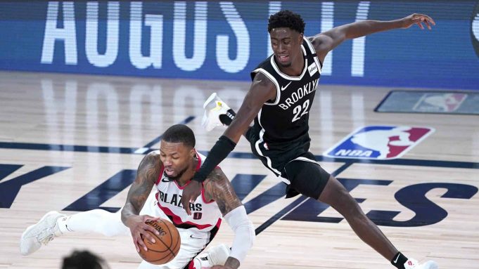 LAKE BUENA VISTA, FLORIDA - AUGUST 13: Damian Lillard #0 of the Portland Trail Blazers falls while chasing the ball against Caris LeVert #22 of the Brooklyn Nets in the second half at AdventHealth Arena at ESPN Wide World Of Sports Complex on August 13, 2020 in Lake Buena Vista, Florida.